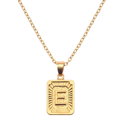 Gold necklace with a rectangular pendant featuring the letter 'E' on a white background
