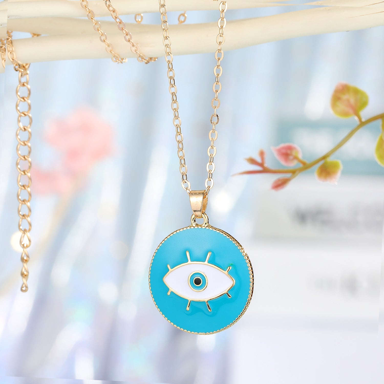 Necklace with a blue eye pendant on a blurred natural background