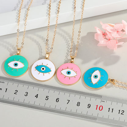 Four colorful eye-shaped pendants on gold chains with a ruler for scale.