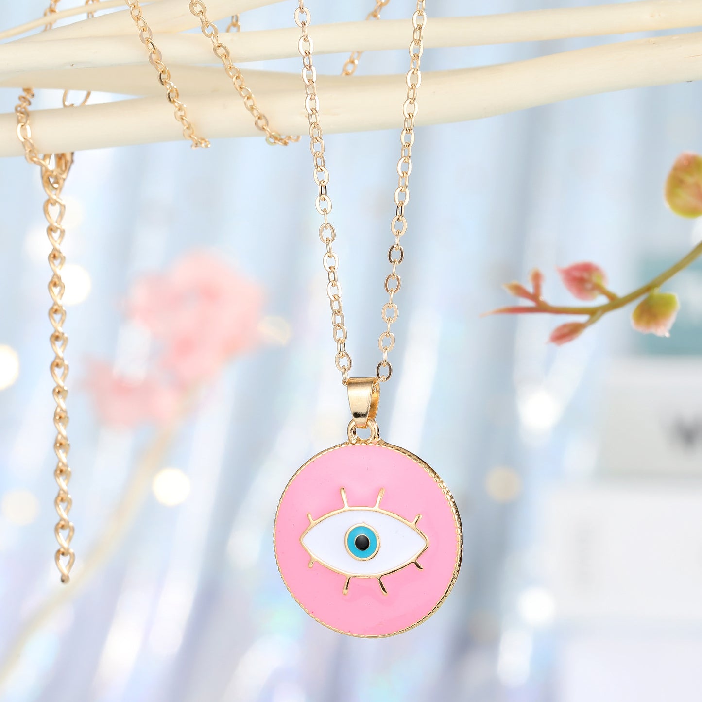 Necklace with a pink eye-shaped pendant on a blurred floral background