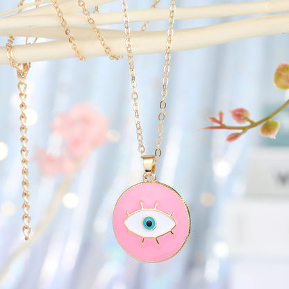 Necklace with a pink eye-shaped pendant on a blurred floral background