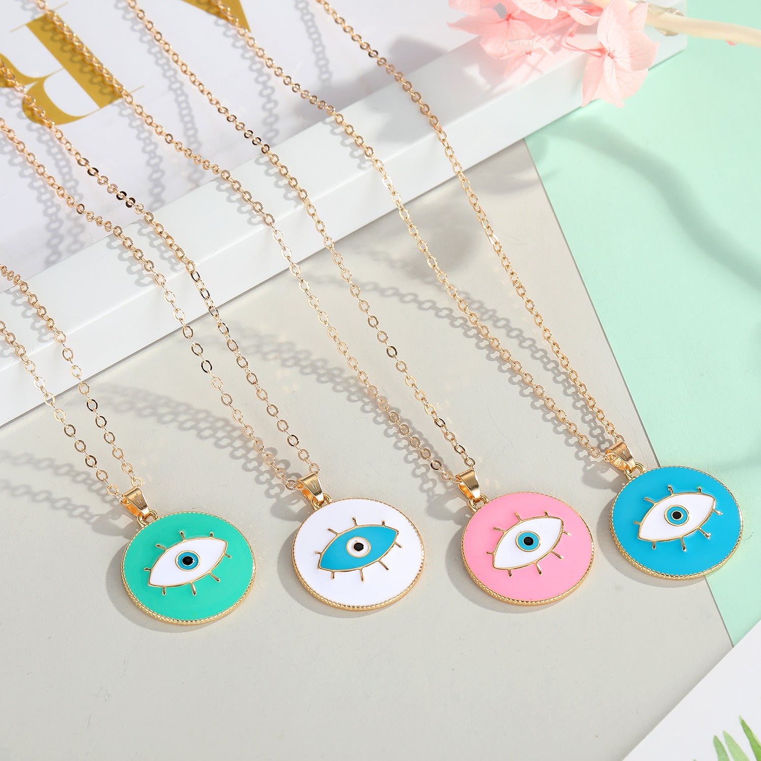 Five necklaces with colorful evil eye pendants on a light background