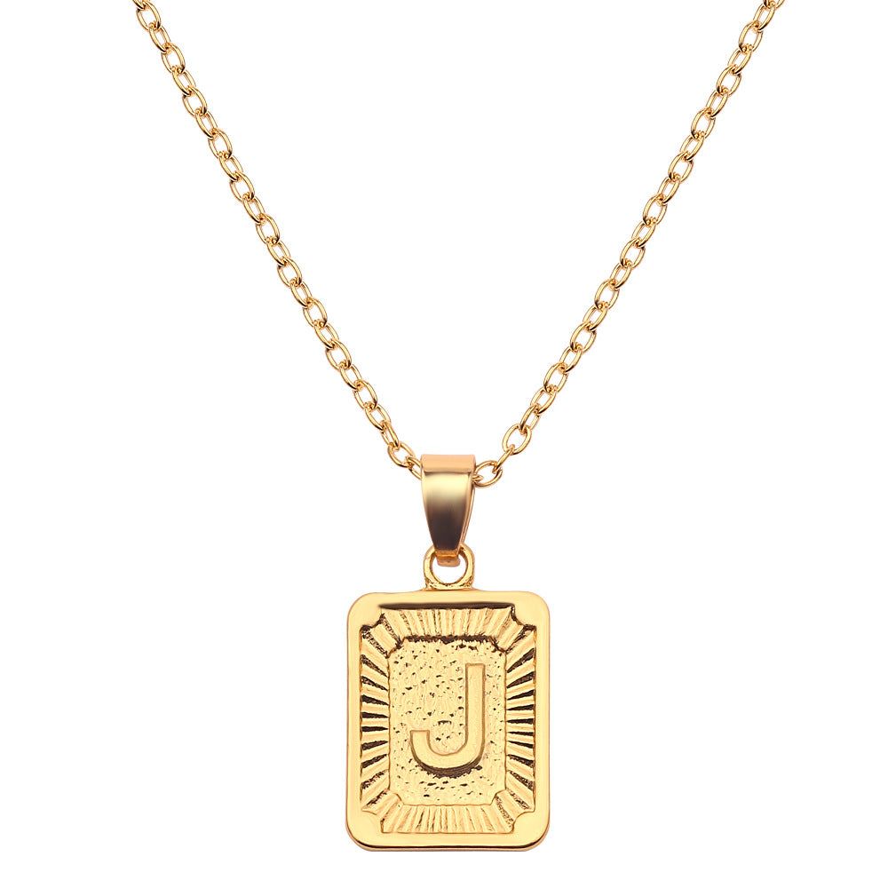 Gold necklace with a rectangular pendant featuring the letter 'J' on a white background