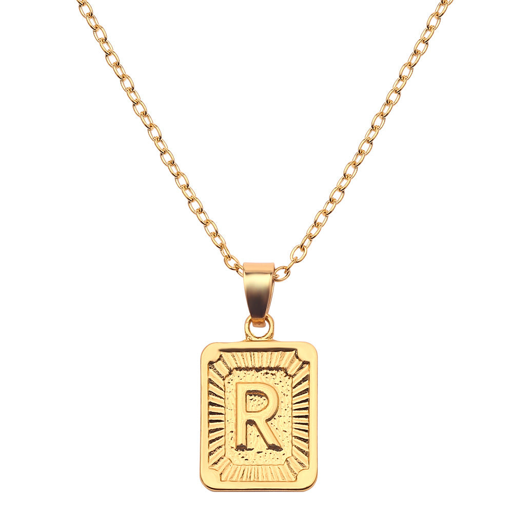 Gold necklace with a pendant featuring the letter 'R' on a white background