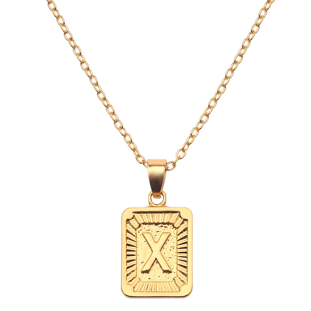 Gold necklace with a rectangular pendant featuring the letter 'X' on a white background