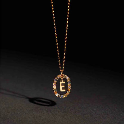 Gold necklace with a pendant featuring the letter 'E' on a dark background