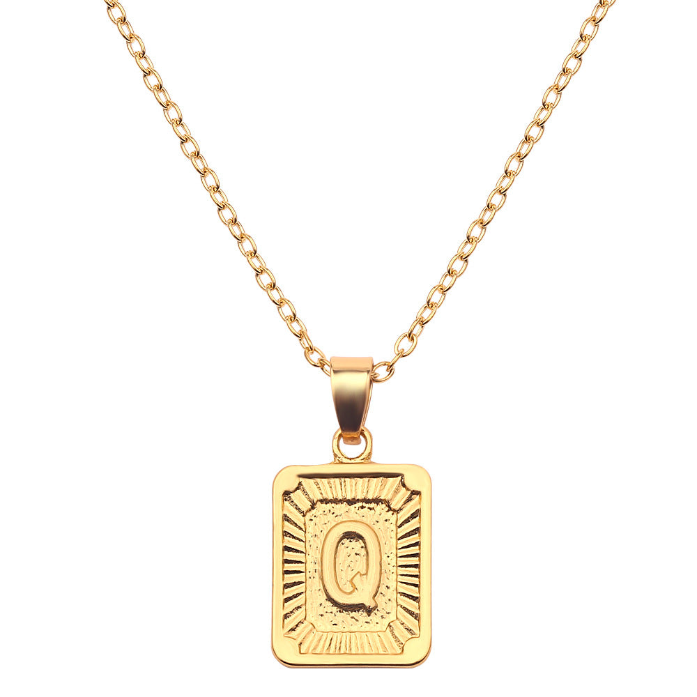 Gold necklace with a rectangular pendant featuring the letter 'Q' on a white background