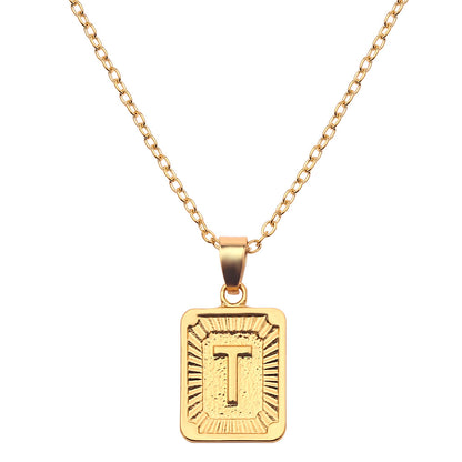 Gold necklace with a rectangular pendant featuring the letter 'T' on a white background