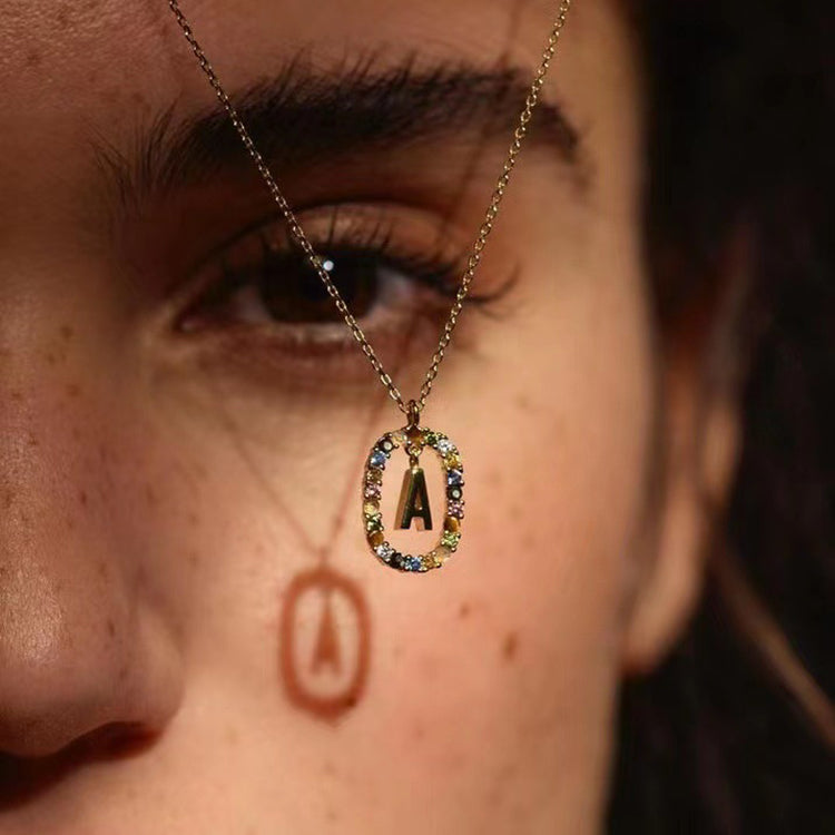 Close-up of a person's face with a gold necklace featuring a letter 'A' pendant.