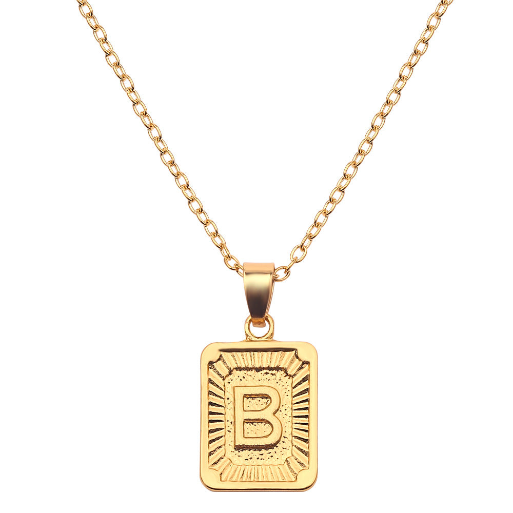 Gold necklace with a rectangular pendant featuring the letter 'B' on a white background