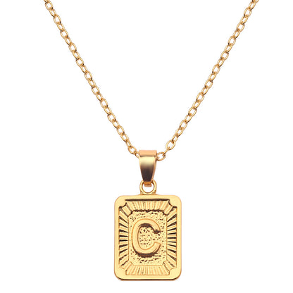 Gold necklace with a square pendant featuring the letter 'C' on a white background