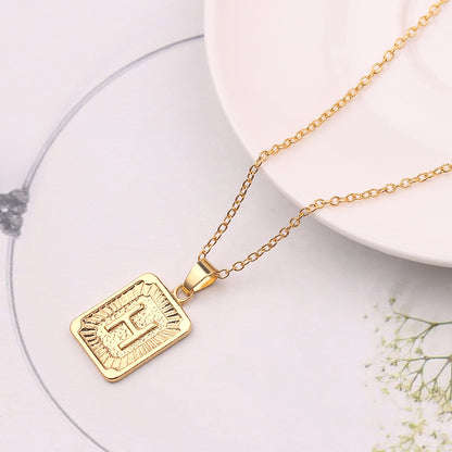 Gold necklace with a rectangular pendant on a white surface