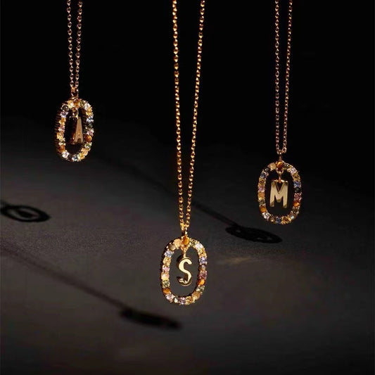 Three gold necklaces with letter pendants on a dark background