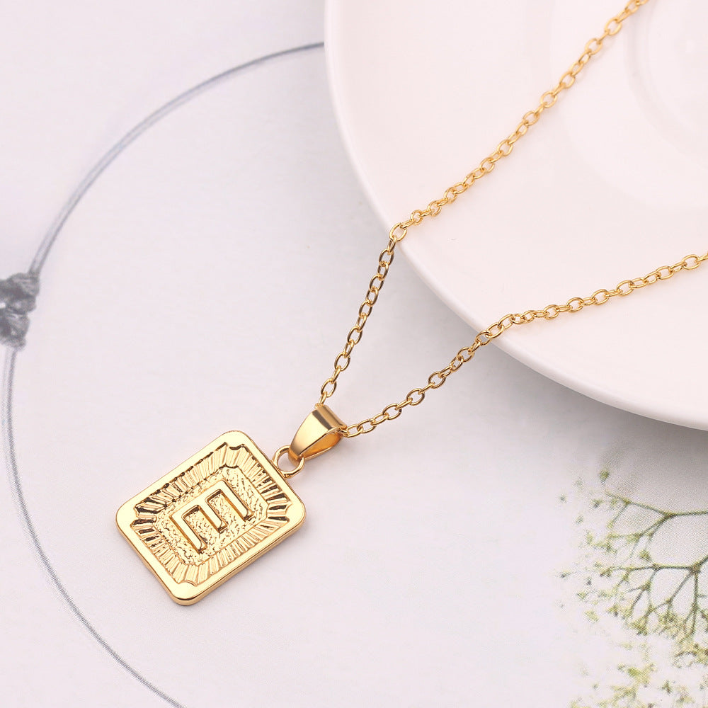 Gold necklace with a rectangular pendant on a white surface