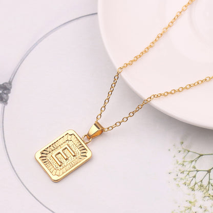 Gold necklace with a rectangular pendant on a white surface
