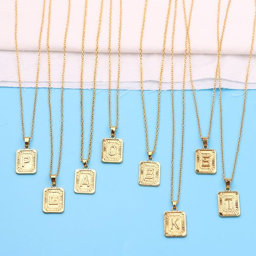 Gold necklaces with square pendants displaying letters on a blue and white background