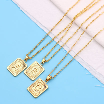 Gold necklaces with square pendants on a blue and white fabric background